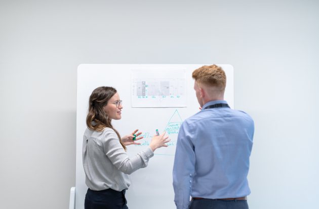 Twee jonge mensen staan voor een whiteboard