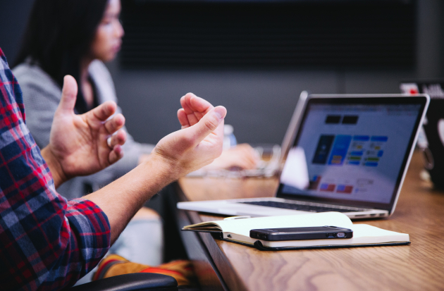 Man zit achter laptop aan een overlegtafel