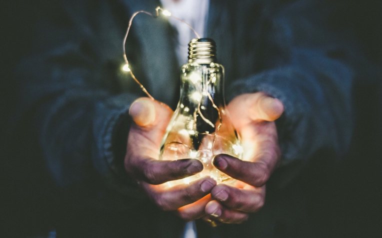 Mannenhanden met lichtpeertje met warm licht