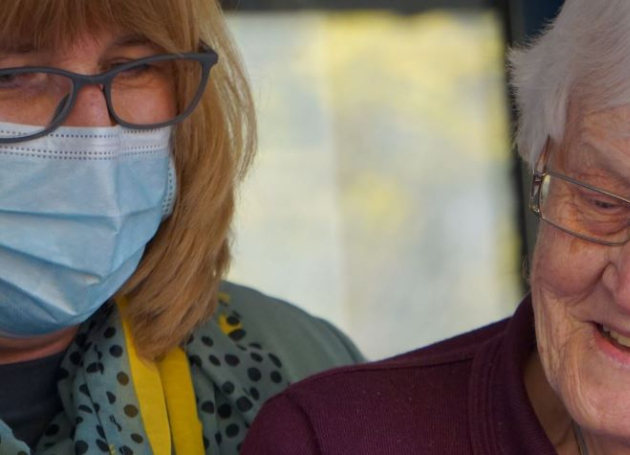 Oudere en jongere met mondkapje mobiel kijken