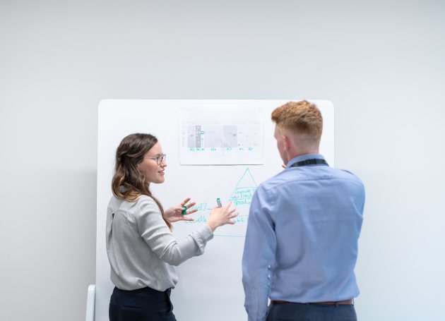 Twee jonge mensen staan voor een whiteboard