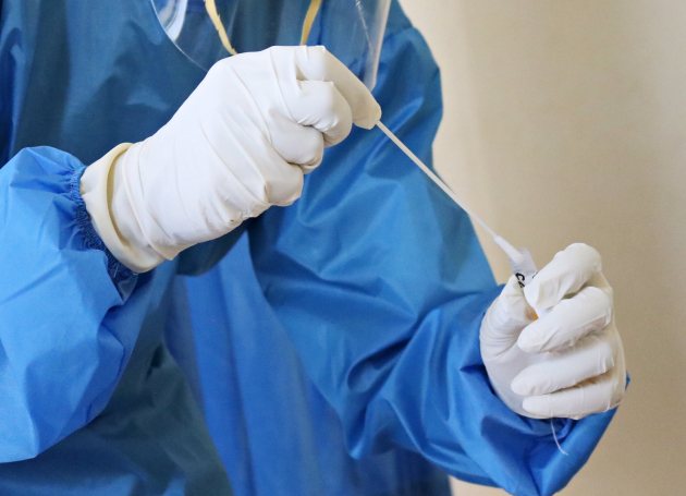 Zorgverlener in beschermende kleding neemt test af