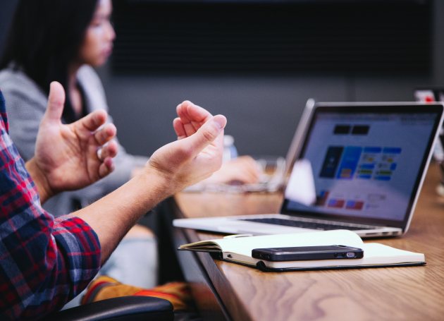 Man zit achter laptop aan een overlegtafel