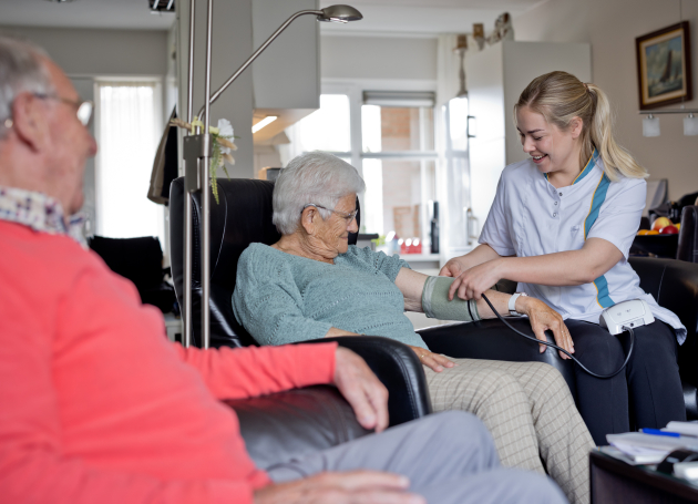 Dame met wijkverpleegkundige en bloeddrukmeter 