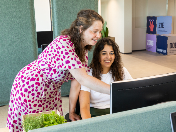 Twee collega's van ActiZ voor een computer scherm